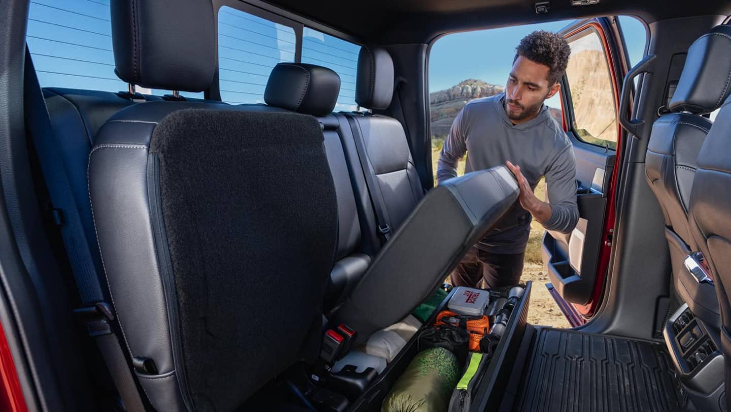 man putting equipment under seat of ford f-150
