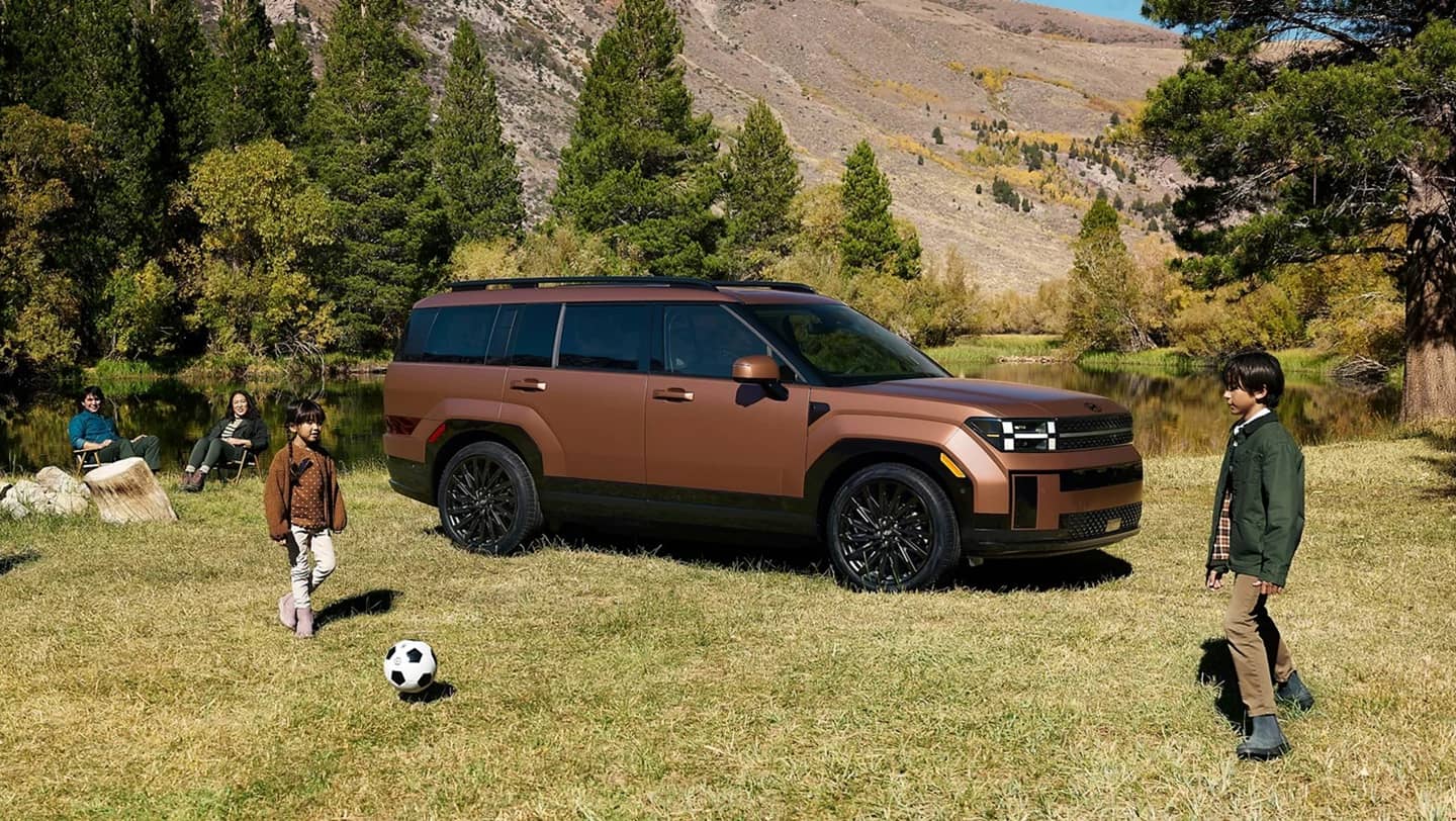 kids playing outside next to parked 2026 hyundai santa fe in grass