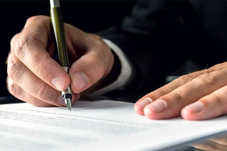Hands of Man in Suit Signing Document