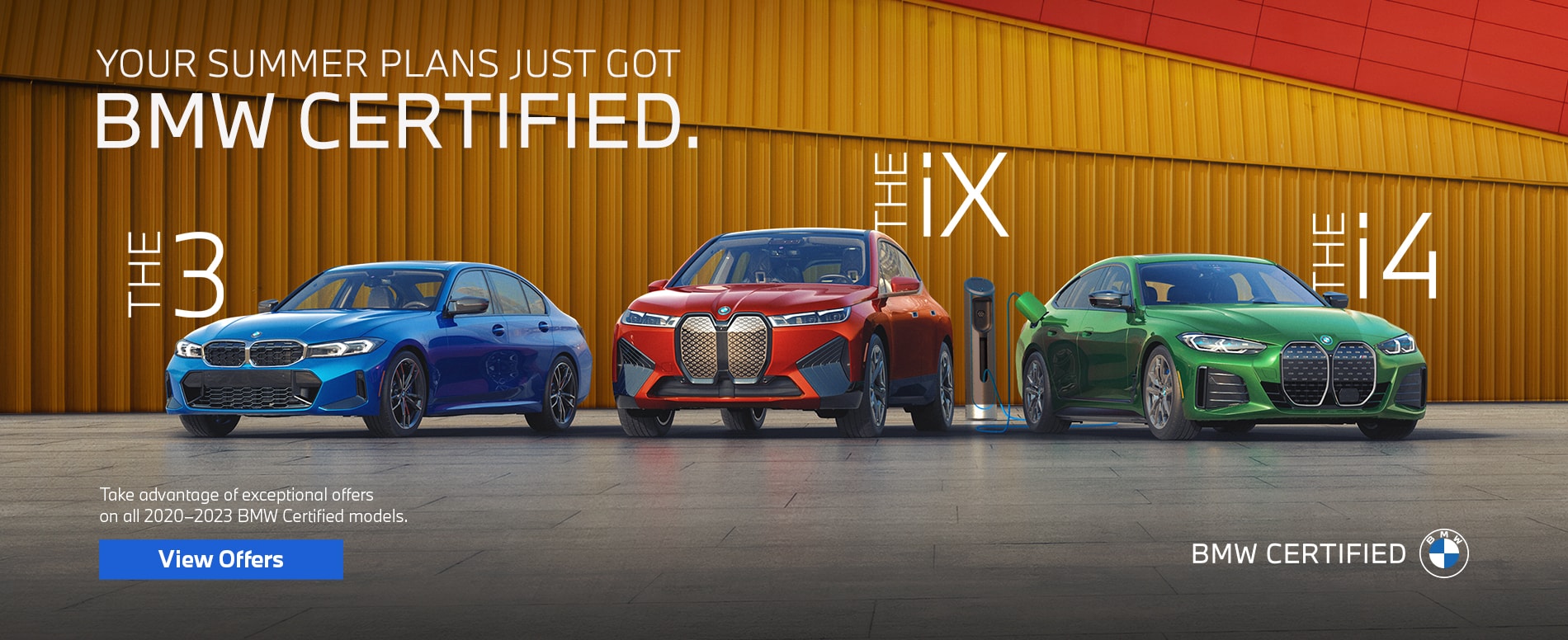A blue, red, and green car parked in front of a colorful industrial city wall.